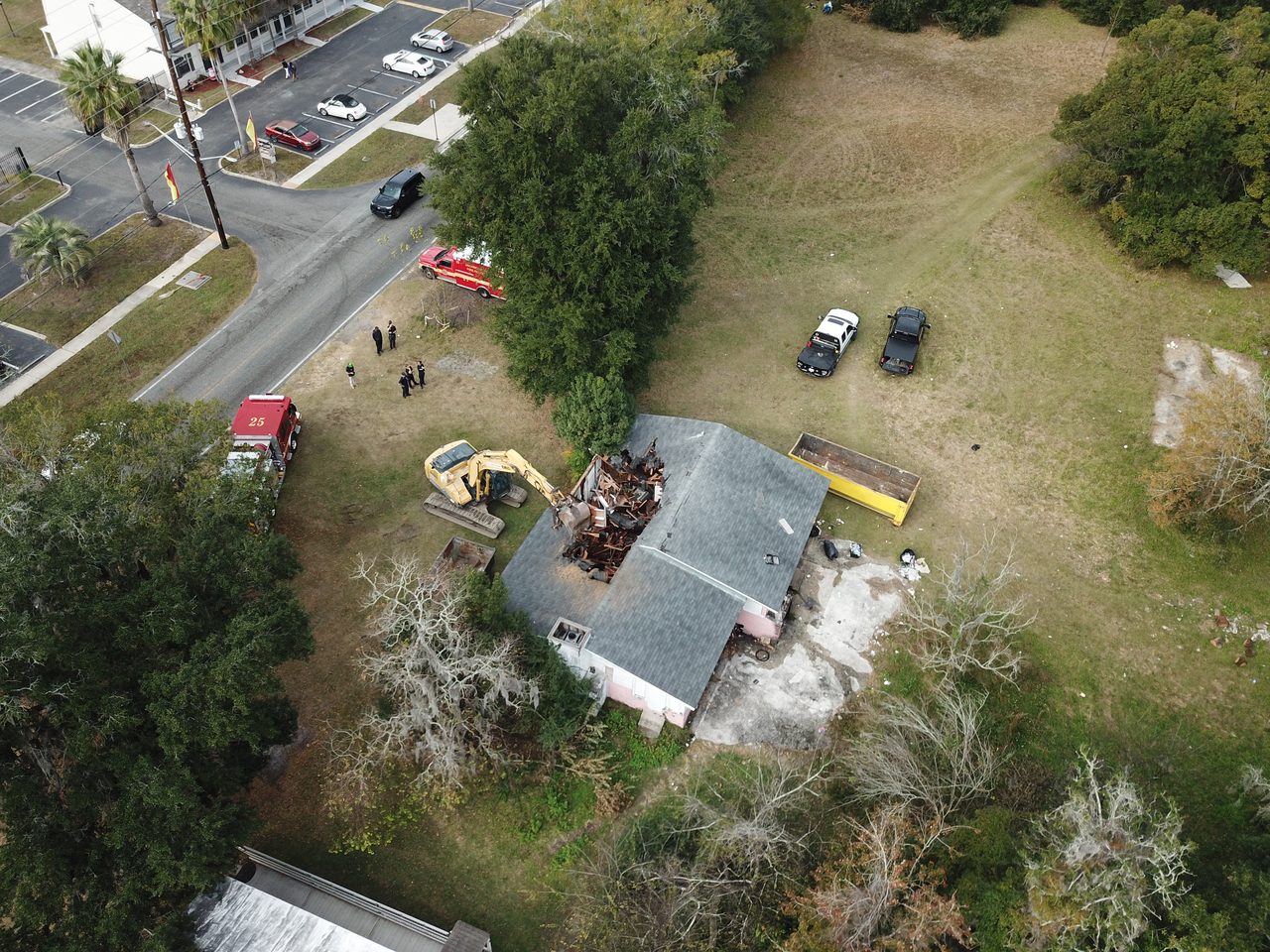 Before: aerial view of a residential structure still standing as a Big Cat excavator begins the teardown, with debris roll-off containers staged on site