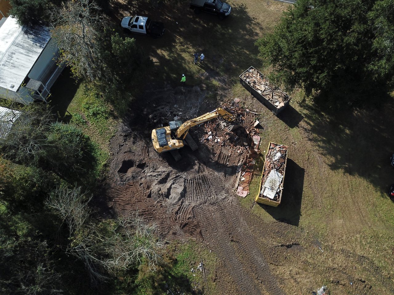 After: the same lot fully cleared and graded flat, with the structure removed and debris hauled into roll-off containers